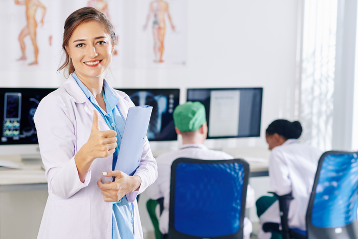 uśmiechnięta studentka w białym kitlu podczas praktyk zawodowych w szpitalu